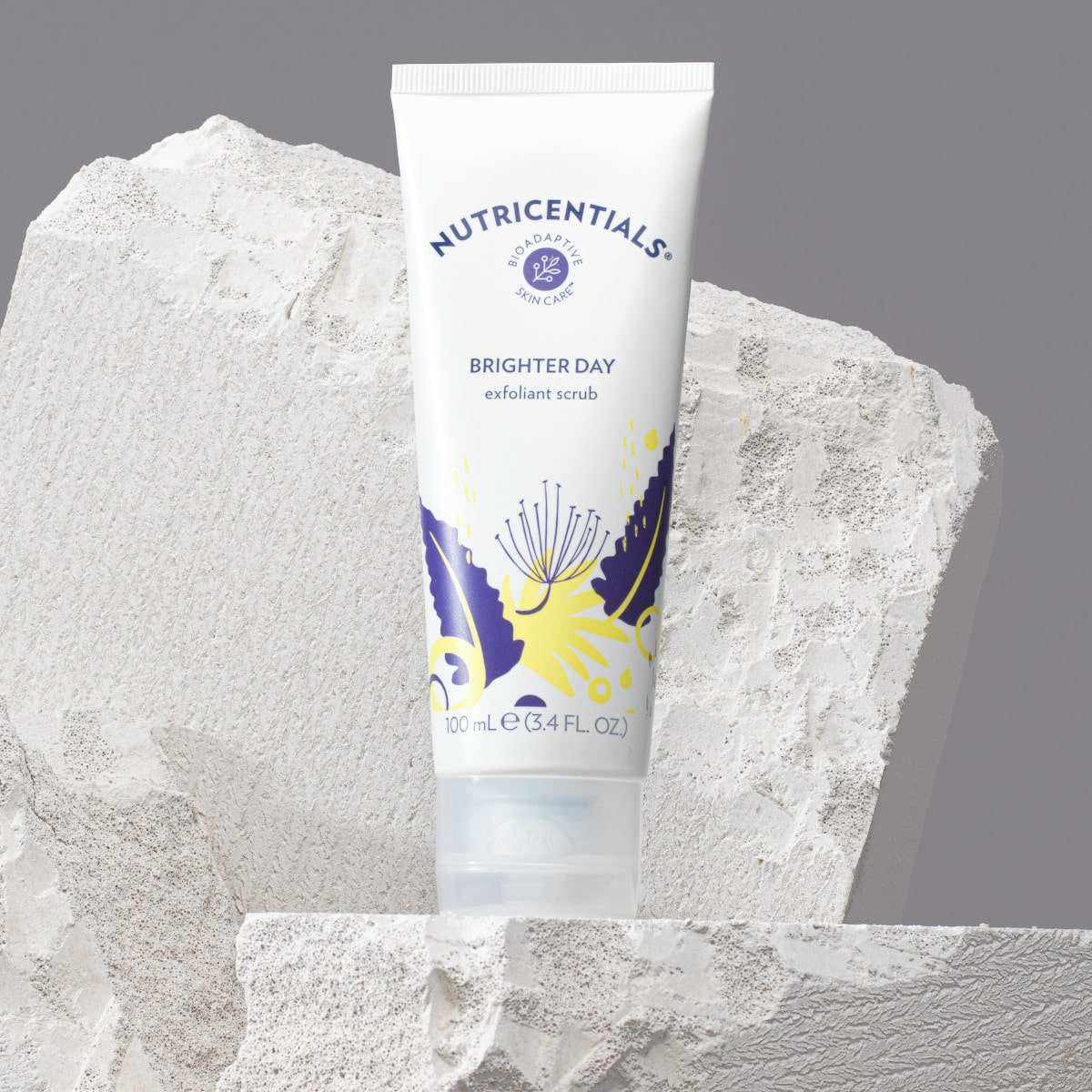 Nutricentials Brighter Day Exfoliant Scrub Tube (100ml) steht auf kleinem weißen "Podest" aus Stein.