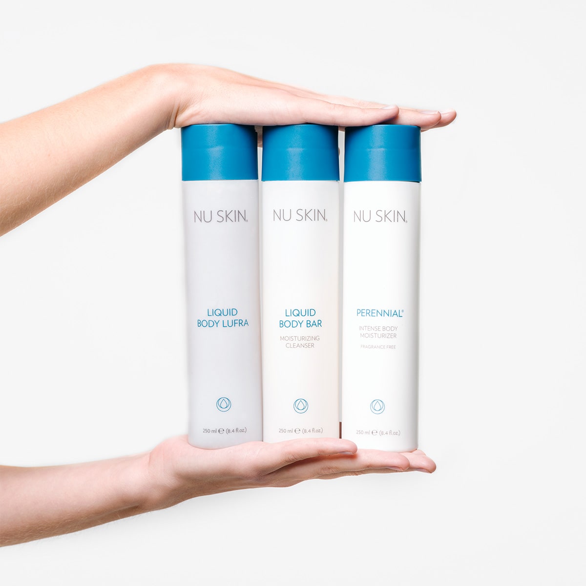 Hände einer jungen Frau präsentieren Nu Skin Produkte: Liquid Body Lufra, Liquid Body Bar und Perennial (alle 250ml).